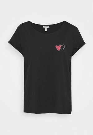 T-shirt noir à manches courtes avec un petit motif cœur rouge et blanc sur la poitrine gauche avec le mot "love."