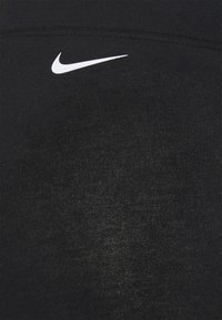Svarta träningsleggings gjorda av texturerat, elastiskt material. Har en liten vit Nike-logotyp på den övre vänstra sidan.