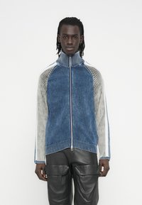 Πουλόβερ με φερμουάρ και ψηλό γιακά, διαθέτει μπλε και γκρι χρωματική αντίθεση, υφές με ριμπ, λουρίδες στις μανσέτες και εφαρμοστή σχεδίαση.