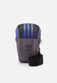 Adidas shoulder bag in gray and blue. Features mesh paneling, three vertical stripes, a logo, and a detachable black strap. Zipper closure.