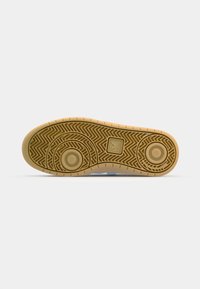 Semelle de chaussure avec une bande de roulement en caoutchouc beige comportant des motifs circulaires et en zigzag, et un petit logo carré près du centre.
