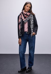 Svart kort jacka, ljusrosa skjorta, blå rakbenade jeans och svarta ankelstövlar. Scarf med rosa och svarta geometriska mönster och leopardtryck.