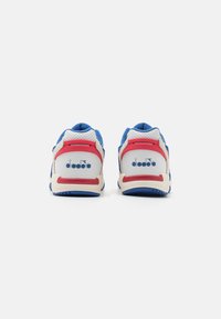 Blue and white athletic shoes with red accents, featuring perforated panels, cushioned heel, and a logo on the back. Textured rubber sole.