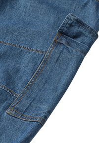 Mâneca din țesătură de denim cu o nuanță albastră, cusături vizibile în portocaliu și un detaliu de buzunar. Textură netedă, având un design clasic.