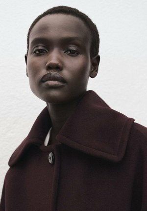 Abrigo de lana color burdeos oscuro con un amplio cuello y un cierre de un solo botón negro. Textura suave, diseño estructurado y cuello alto.