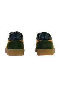 Green suede sneakers with yellow accents, brown rubber sole, and "Gola" branding on the heel. Classic low-top design, cushioned collar.