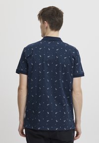 Moška navy polo majica z vzorcem majhnih ananasov in diamantov. Mehka tkanina, kratki rokavi in klasična zasnova ovratnika.
