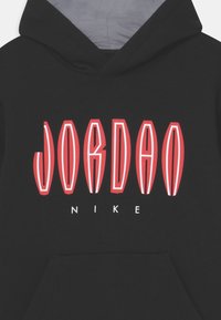 Felpa nera con cappuccio con testo stilizzato "JORDAN" in rosso e bianco e il logo "NIKE" bianco più piccolo sotto il petto.