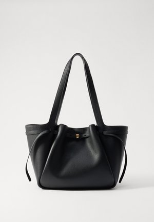 Geantă tote din piele neagră, cu două bretele lungi, un vârf strâns și un accent circular auriu. Textură netedă cu un design minimalist.