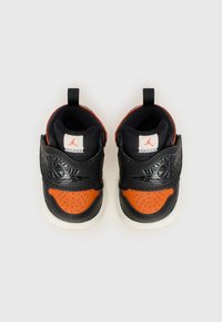 Baskets noires et orange avec un dessus en cuir lisse, une pointe perforée et une semelle blanche. Comprend une sangle avec logo et des poignées.
