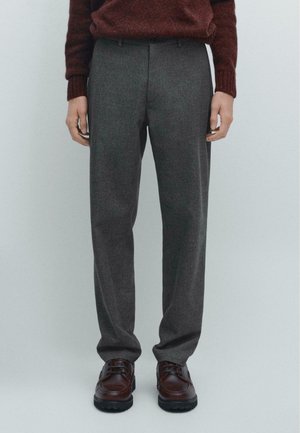 Gray wool trousers with a straight fit, featuring a subtle herringbone pattern, front pockets, and a polished brown leather shoe.