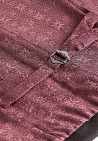 Tissu bourgogne à motifs avec des dessins circulaires et floraux, agrémenté d'une fermeture métallique. Surface texturée avec un léger éclat.