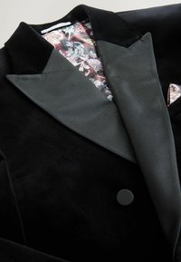 Schwarze Samt-Tuxedojacke mit Satin-Revers, Ein-Knopf-Verschluss und farbenfrohem Paisley-Muster-Futter. Eine Einstecktuch ist im Lieferumfang enthalten.