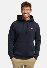 Sudadera azul marino de mezcla de algodón, con un bolsillo frontal, cordones y un logo rojo en el pecho. Textura suave, diseño casual.