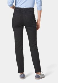 Pantalons en denim noir avec une taille élastique, cinq poches et une coupe ajustée. Le tissu a une texture lisse et le design présente une coupe classique.