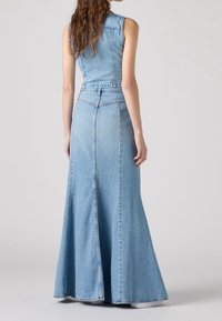 Vestido maxi de mezclilla en azul claro, sin mangas, con cuerpo ajustado y falda acampanada con detalles de costura. Textura suave, diseño casual, hasta los tobillos.