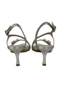 Sandali con tacco alto argento con delicate cinghie alla caviglia, finitura metallica liscia e tacchi a stiletto sottili. Design semplice con accenti minimalisti.