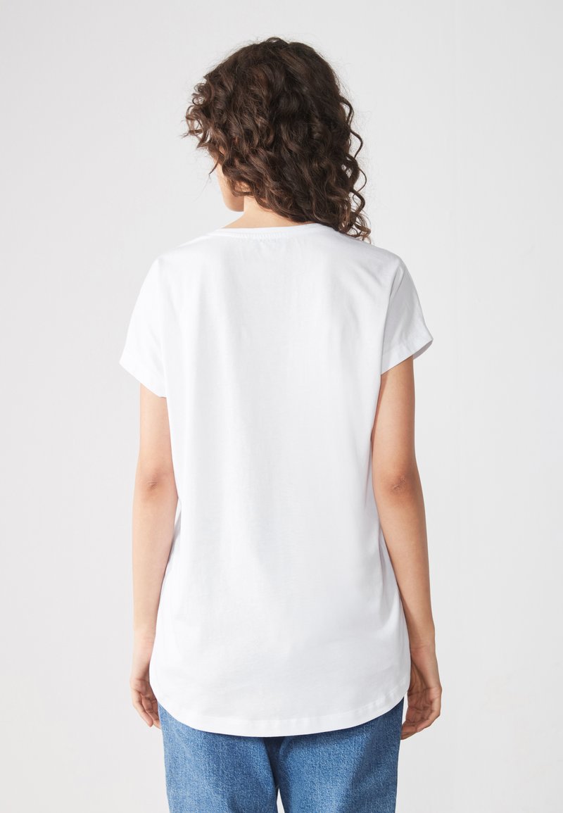 T-shirt en coton blanc à manches courtes, encolure ras du cou et coupe décontractée. Texture lisse et ourlet légèrement arrondi à l'arrière.