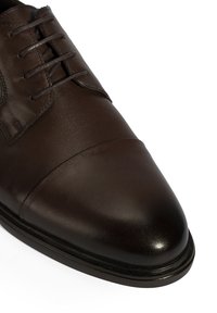 Bruine leren dresschoenen met een gladde afwerking, puntige neus en zes oogjes voor vetersluiting; beschikken over een klassiek ontwerp en minimale stikdetails.