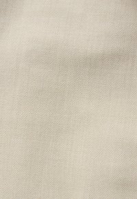 Beige stof met een fijne, geweven textuur, voorzien van een subtiel patroon, lichtgewicht en glad aanvoelend. Geschikt voor verschillende textieltoepassingen.