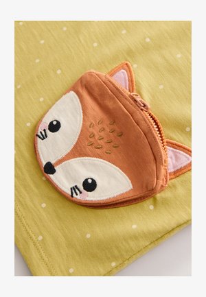 Zöld szövet fehér pöttyökkel, amelyen narancssárga róka formájú cipzáras zseb található, hímzett arcrészletekkel, beleértve a szemeket és a füleket.