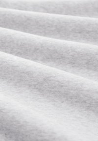 Biely textil s hladkou, jemnou štruktúrou, s jemnými farebnými variáciami. Materiál sa zdá byť ľahký a mierne elastický.
