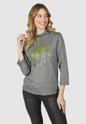 Hoodie gris avec cordon de serrage en jaune néon, présentant un texte graphique argenté "Amazing" et un motif floral. Coupe décontractée avec des manches à trois quarts.