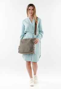 Borsa a tracolla grigia con superficie testurizzata, chiusura con zip e tracolla regolabile. Presenta tasche anteriori e un logo grafico sul lato.