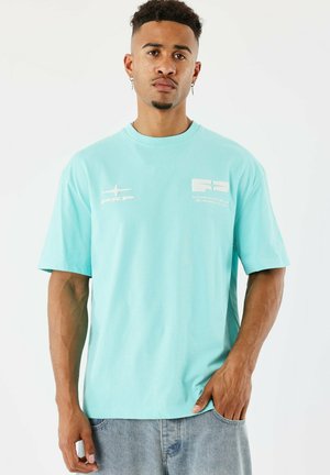 T-shirt en coton turquoise avec un col rond, des manches courtes et des graphismes imprimés blancs sur le devant. Conçu avec une coupe décontractée.