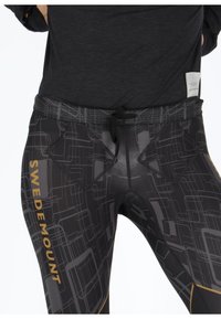 Black leggings with a geometric pattern in shades of gray and gold. Features a drawstring waist and two front pockets. Stretch fabric.