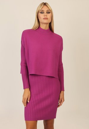 Fuchsia gestricktes Kleid und Pullover-Set. Der Pullover hat einen hohen Kragen und einen lockeren Schnitt; das Kleid zeichnet sich durch eine gerippte Textur und eine taillierte Silhouette aus.