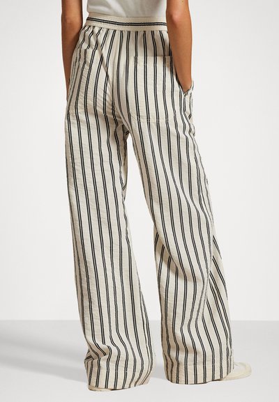 Pantalons larges en tissu léger et texturé dans un coloris crème avec des rayures verticales noires. Avec une taille élastique et des poches latérales.
