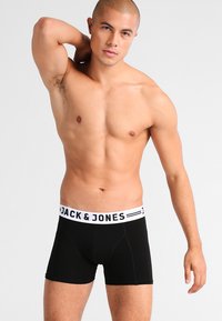 Fekete boxer alsónadrág, puha anyagból, fehér derékszíjjal, rajta a "JACK & JONES" márkajelzéssel és szoros, testre simuló fazonnal.