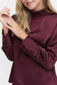 Bordowa bluzka z długim rękawem, wysokim kołnierzem, gładką, satynową fakturą i detalami z guzikami na rękawach, cechująca się luźnym krojem i minimalistycznym designem.