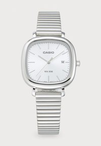 Montre Casio avec un boîtier carré en argent, un cadran blanc, un bracelet en métal argenté nervuré et un affichage de la date. Résistante à l'eau jusqu'à 50 mètres.