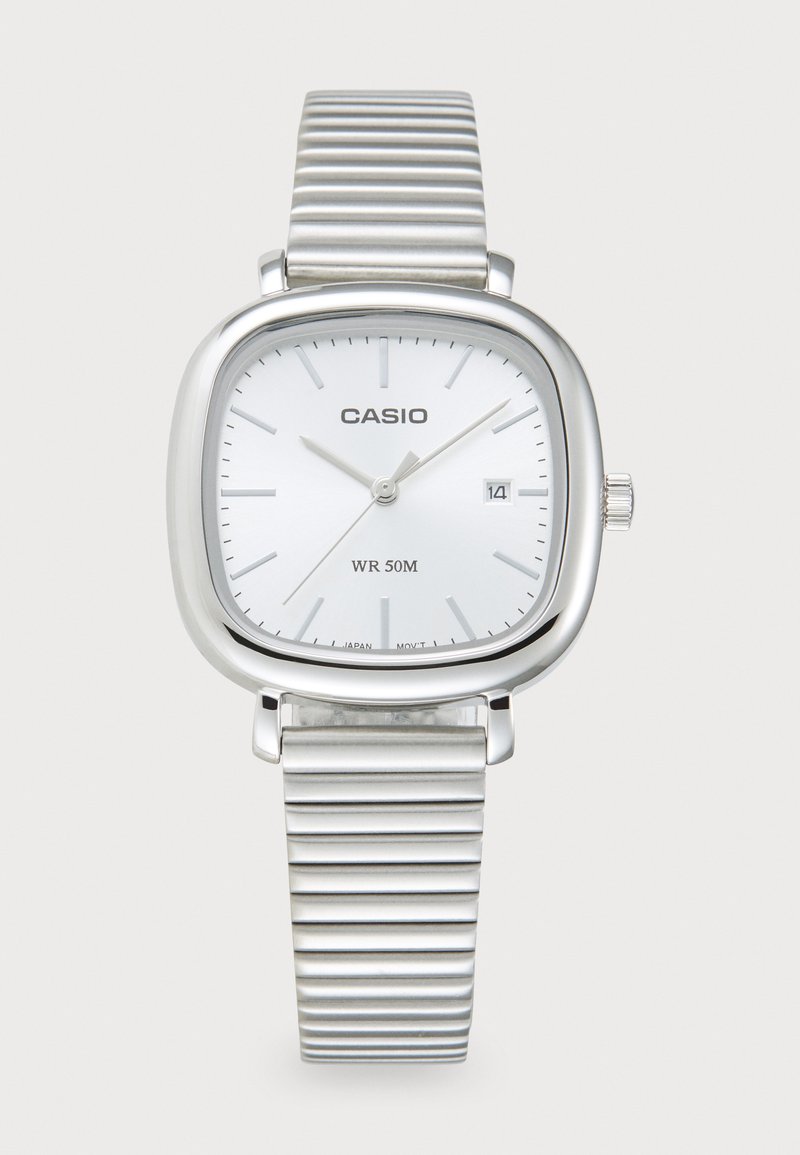 Montre Casio avec un boîtier carré en argent, un cadran blanc, un bracelet en métal argenté nervuré et un affichage de la date. Résistante à l'eau jusqu'à 50 mètres.