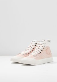 K vysoké tenisky s bledě růžovým plátěným svrškem, bílou gumovou podrážkou, černými ventilačními otvory a logem na boku. Design se šněrovací uzávěrou.