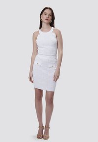 Set di maglia bianco composto da due pezzi, con una canotta senza maniche decorata con dettagli in oro e una gonna aderente con tasche frontali e una texture a motivi.