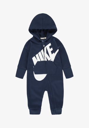 Temno modra kapuca kombinezon iz mehkega blaga, s belim logotipom Nike, sprednjim žepom in zadrgo po celotni dolžini.