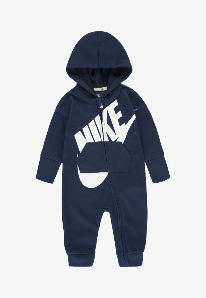 Tengerészkék kapucnis overál puha anyagból, fehér Nike logóval, elülső zsebbel és teljes hosszúságú cipzárral.
