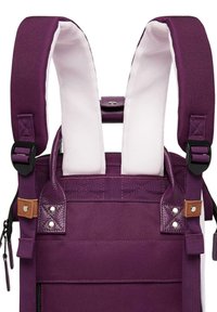 Purple backpack with padded white straps, metal hardware, textured fabric, and brown leather accents. Features adjustable straps and zippers.