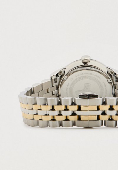 Μπρασελέ ρολογιού από ανοξείδωτο ατσάλι με χρυσούς συνδέσμους στη μέση και χαραγμένο λογότυπο Vivienne Westwood στο πίσω μέρος της κάσας του ρολογιού.