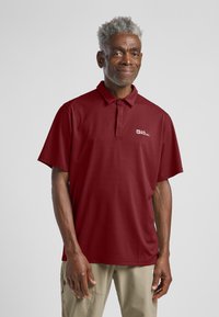 Bordeaux polo shirt met een kraag, korte mouwen en een logo op de linkerkant van de borst. De stof lijkt lichtgewicht en gestructureerd.