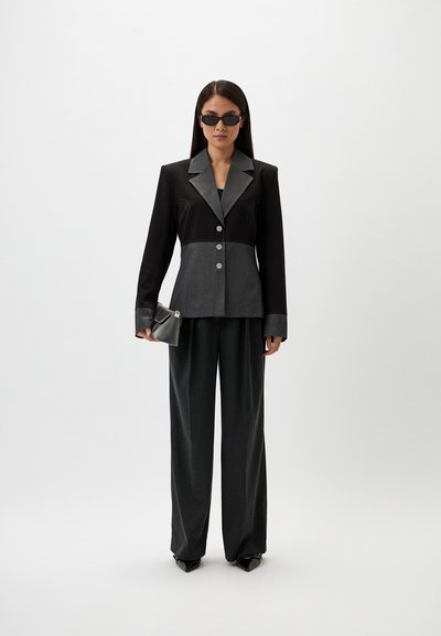 Black and gray tailored blazer with a contrasting collar, three buttons, paired with wide-leg trousers and a small gray clutch.