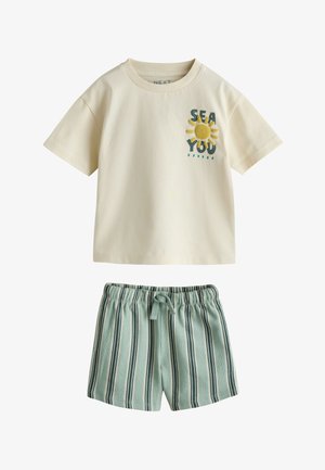 Kremfarvet kortærmet skjorte med gul sol og tekst "SEA YOU" kombineret med lyseblå og mørke stribede shorts med elastisk talje.