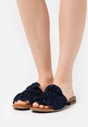 Navyblauwe suède instapsandalen met een grote strikdetail op de bovenkant, met een platte houten zool en een open te ontwerp.