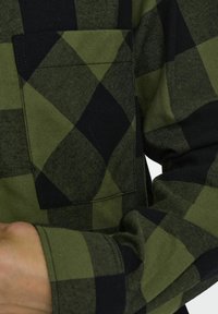 Groen en zwart geblokt overhemd, met een vierkante zak, gestructureerde stof en lange mouwen, met een opvallend ruitpatroon.