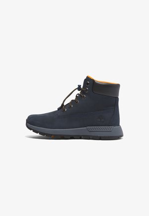Marineblaue Wildleder-Ankle Boots mit oranger Innenauskleidung, ausgestattet mit Metallösen, flachen Schnürsenkeln und einer strukturierten grauen Gummisohle. Timberland-Logo an der Seite.