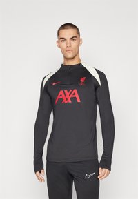 Czarna długo rękawowa koszulka treningowa z wysokim kołnierzem, białymi akcentami na ramionach, czerwonym logo i napisem "AXA". Materiał wydaje się gładki i dopasowany.