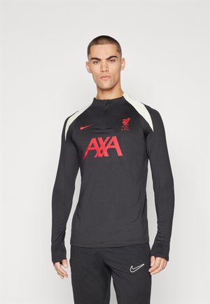 Maglia da allenamento nera a maniche lunghe con colletto alto, accenti bianchi sulle spalle, logo rosso e testo "AXA". Il tessuto appare liscio e aderente.